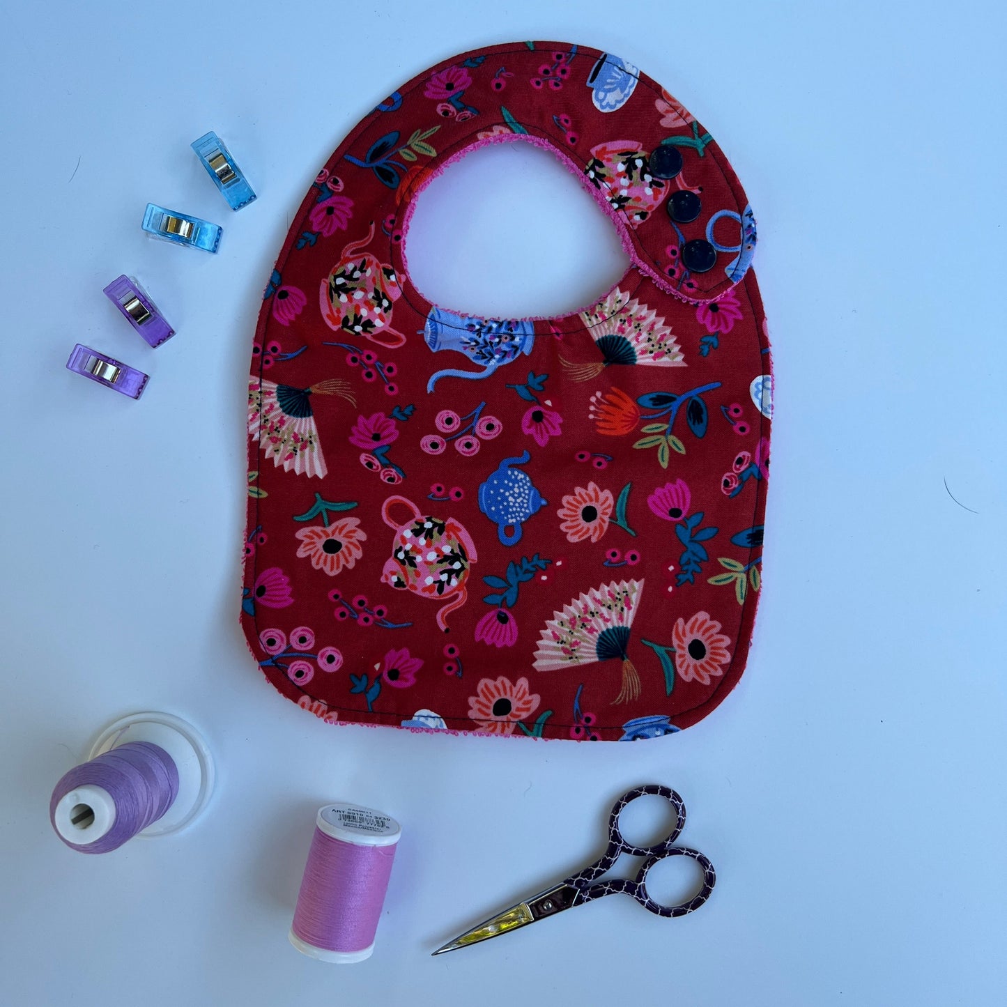  fabric with floral and teapot pattern on a white background, with sewing supplies around.