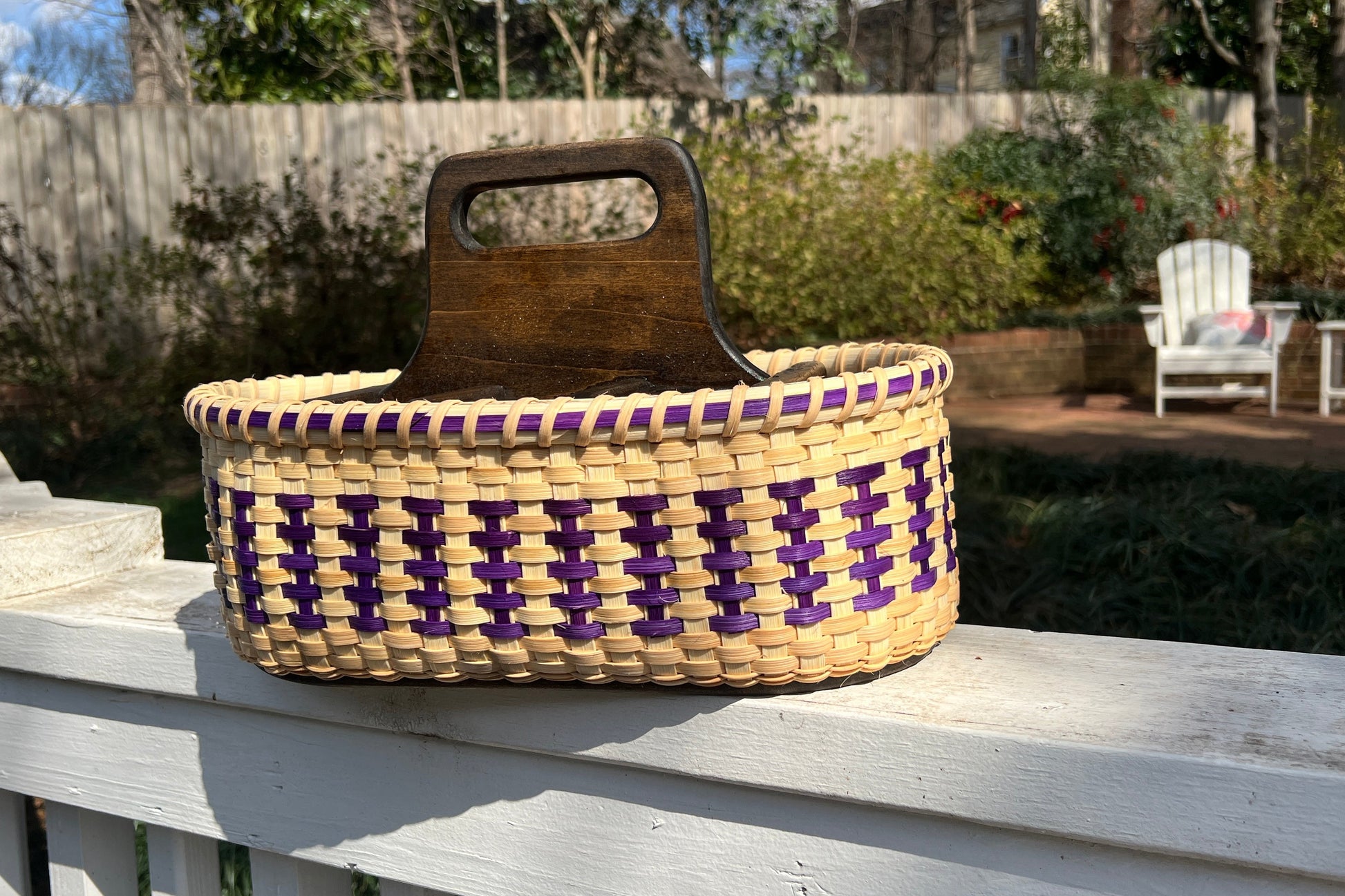 Woven basket with a wooden handle on a wooden deck