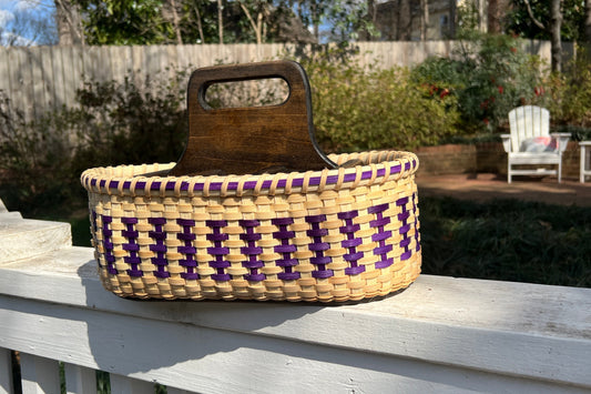 Woven basket with a wooden handle on a wooden deck