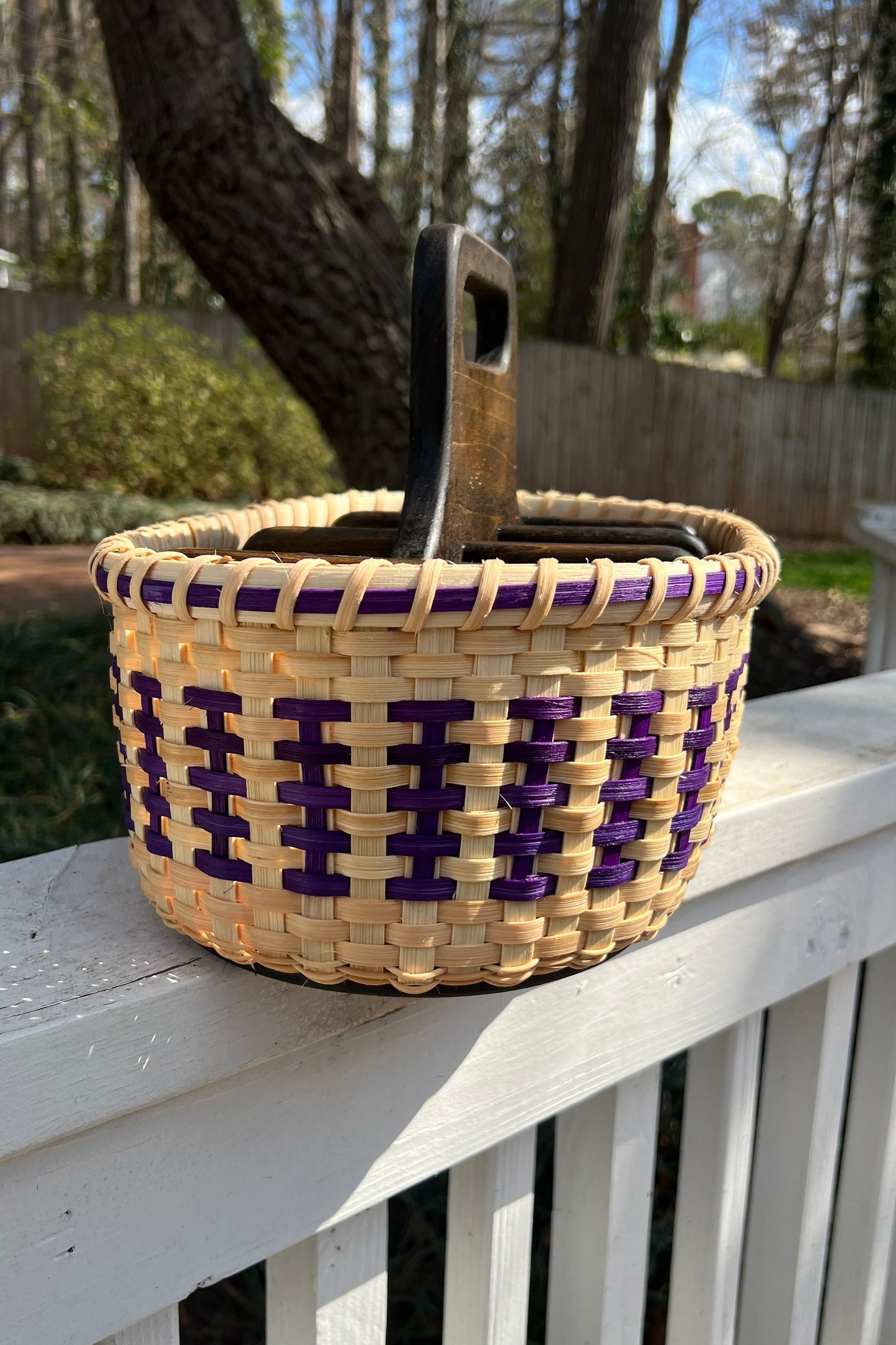Woven basket with purple accents on a white railing outdoors