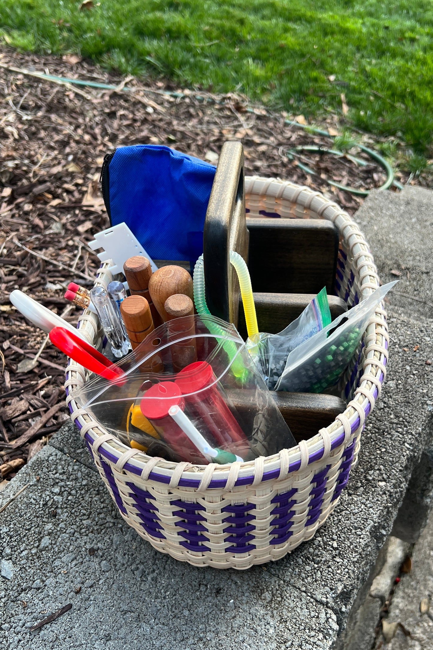 Basket filled with various items on a concrete surface with grass in the background